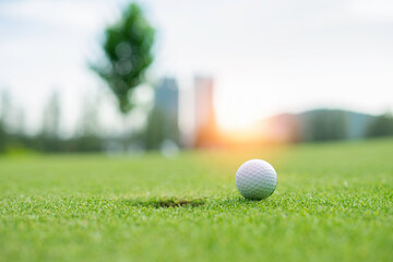 Close-up shot of golf ball resting on the green at sunset