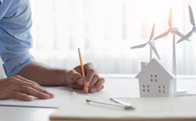 A construction engineer is working on a wind turbine planning for a new project on a desk in the...