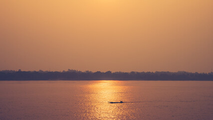 Beatiful golden sunlight landscape and silhouette with small fishing boat on the river