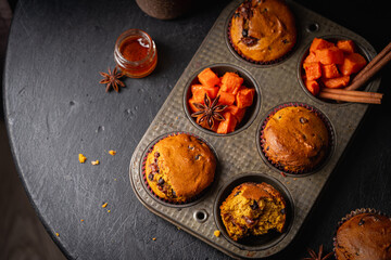 Homemade spicy pumpkin muffins or cupcakes with chocolate on a metal rack, top view. Autumn dessert. Selective focus