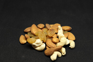 The healthy dry fruit, almond, cashews, and grapes. On a black background