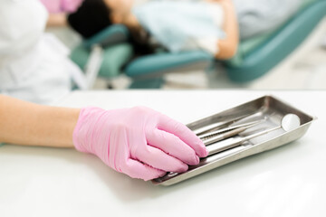 Obraz premium stomatologist hand pink rubber gloves taking professional medical instrument for patient examination