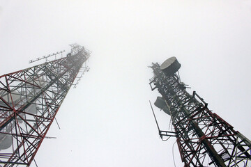 View looking up at two telecommunication masts tailing off into the mist. Microwave link and TV transmitter towers. No people.