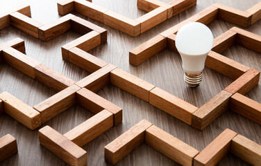 Light bulb in the maze game built by wood blocks, finding the right way to the success, idea concept