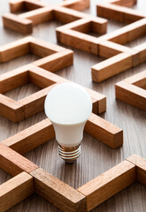 Light bulb in the maze game built by wood blocks, finding the right way to the success, idea concept