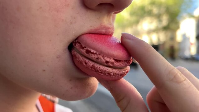 Teenage girl brown-haired woman with a mole above her lip eats makarun close-up slowly biting it off and blows with pleasure. High quality 4k footage