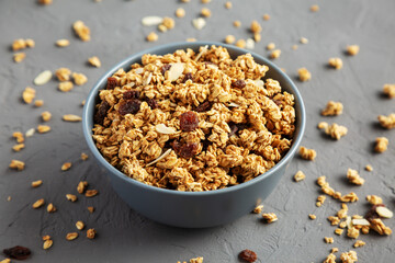 Homemade Granola with raisins and almonds  in a Bowl on a gray background, side view.