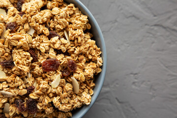 Homemade Granola with raisins and almonds  in a Bowl on a gray background, top view. Flat lay, overhead, from above. Copy space.