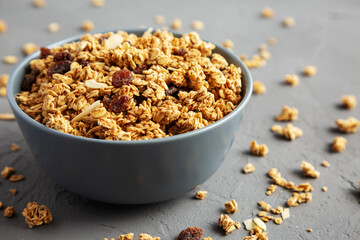 Homemade Granola with raisins and almonds  in a Bowl on a gray surface, side view.