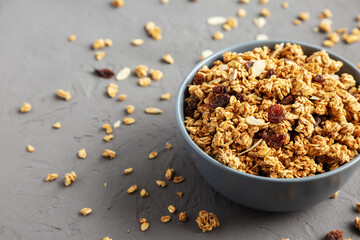 Homemade Granola with raisins and almonds  in a Bowl on a gray background, side view. Space for text.