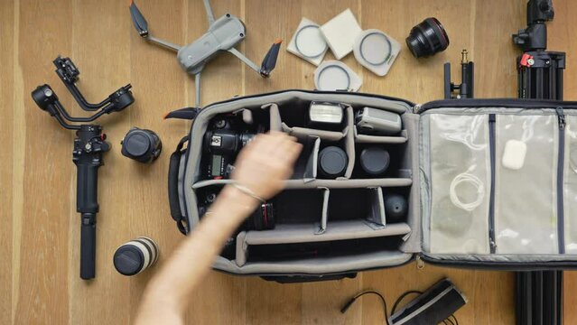 Professional  photographer packs smart backpack with equipment screw the stick into the remote controler. Top view on suitcase with lens camera and drone drone and gimbal