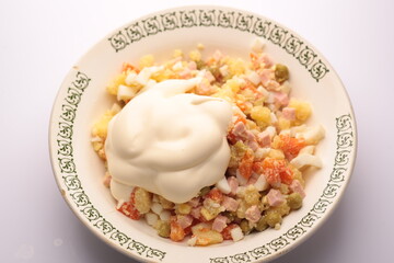 Russian salad Olivier with mayonnaise on plate. Light background. Top view, flat lay.