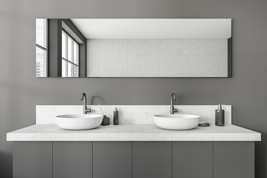 Grey bathroom interior with sink and mirror, accessories on deck
