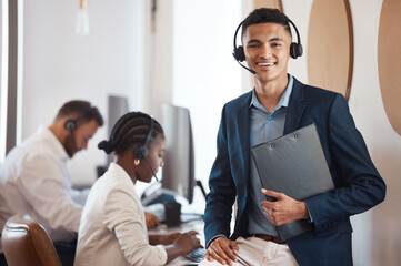As manager, I always keep my team on track. Portrait of a young call centre agent holding a folder in an office with his colleagues in the background.