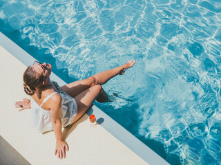 Fashionable woman sitting by the pool on the empty deck of a cruise liner. Closeup, outdoor, view...