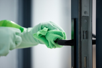Thoroughly disinfect every surface of your home. Shot of a woman wiping down the handles on her...