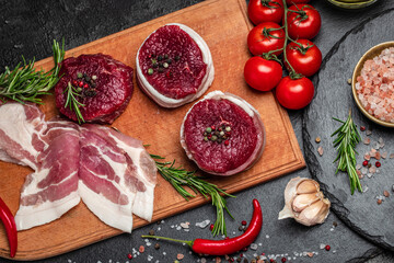 Beef medallions wrapped in bacon with rosemary and spices, Raw beef meat steak Tenderloin fillet on a cutting board. Top view. Copy space