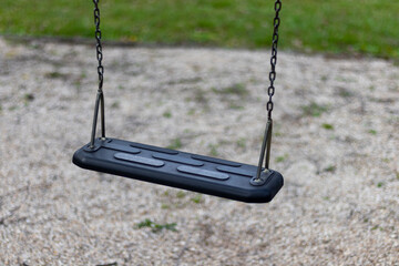 Empty black swing detail on playground