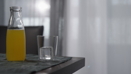 lemonade in tumbler glass with ice cube on wood table