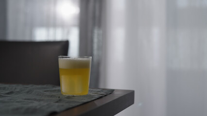 lemonade in tumbler glass with ice cube on wood table