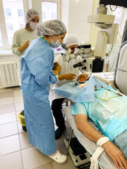 Ophthalmologist surgeon, together with assistants and nurse, performs complex operation to restore vision in a patient