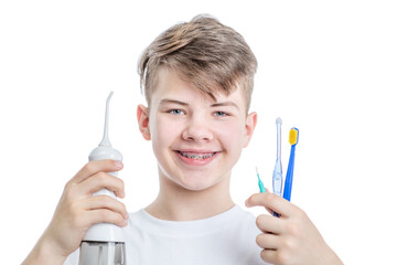 Orthodontic treatment. Dental Care Concept. Young smiling boy with brackets holds irrigator and...
