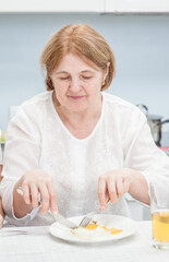 Obraz na płótnie Canvas Senior woman is having breakfast in the kitchen at home