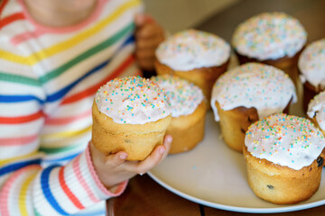 Closeup of little child holding traditional Easter cake called paska in Russian and Ukrainian. Happy child with sweet sprinkles on holiday.
