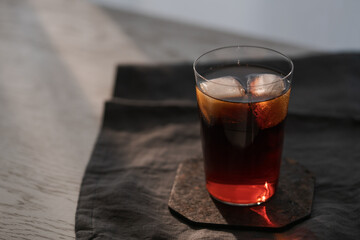 Cola with ice in tumbler glass on wood table with copy space