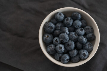 Fresh washed blueberris in white bowl on linen cloth