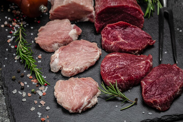 Different types of raw pork meat and beef on a dark background. various types of fresh meat pork and beef. Restaurant menu, dieting, cookbook recipe top view