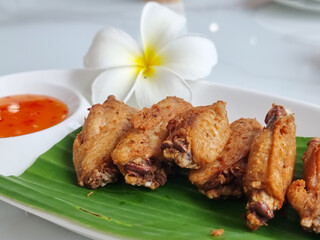 Fried chicken wings on a plate with rests and a cup of dipping sauce