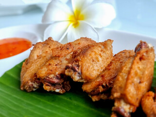 Fried chicken wings on a plate with rests and a cup of dipping sauce