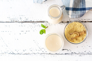 Millet milk in glass, jar and bowl on white wooden table with copy space © TATIANA Z