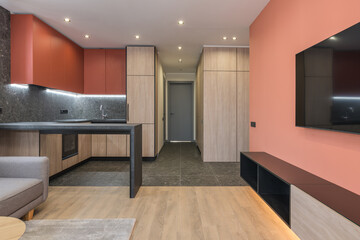 Modern design of a residential apartment with Marsala-colored walls, a gray sofa and a wood kitchen