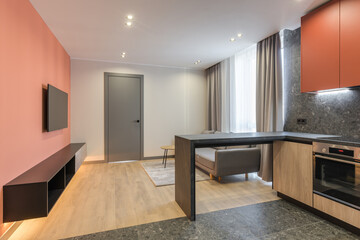 Modern design of a residential apartment with Marsala-colored walls, a gray sofa and a wood kitchen