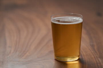 Apple cider in tumbler glass on walnut wood table with copy space