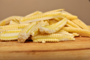 Closeup of baby corn on wooden cutting board, side view of baby corn