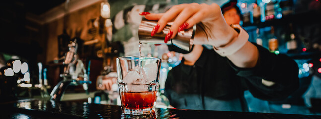 bartender hand making negroni cocktail. Negroni classic cocktail and gin short drink with sweet...