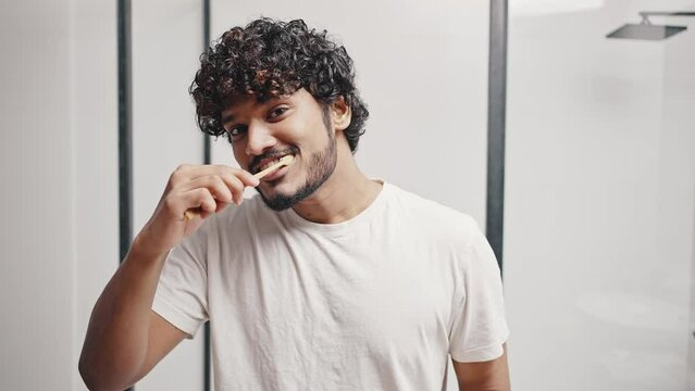 Young Indian man puts paste on brush to clean teeth at home