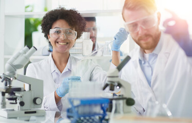 Smiling scientists looking at camera arms crossed in laboratory