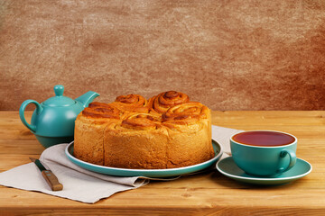 Homemade cinnamon rolls from yeast dough and cup of tea on white wooden table. Copyspace.