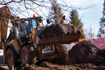 The excavator backfills the pit with the front bucket. Moves soil around the construction site....