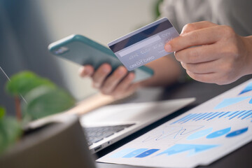 Close up shot of females hands holding credit card typing message on smart phone for shopping online