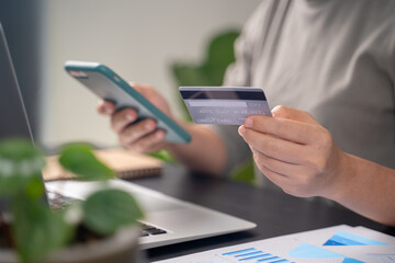 Close up shot of females hands holding credit card typing message on smart phone for shopping online