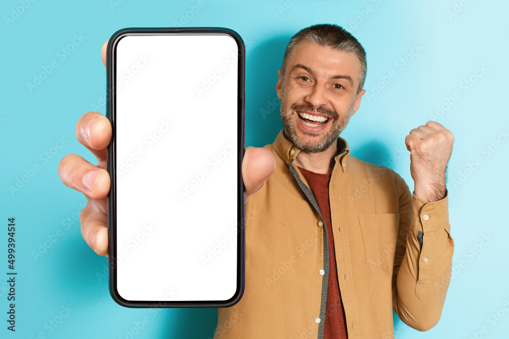 Poster man showing big smartphone screen gesturing yes over blue background