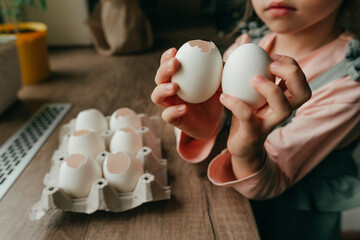 Little girl holding an egg and an empty eggshell in her hands