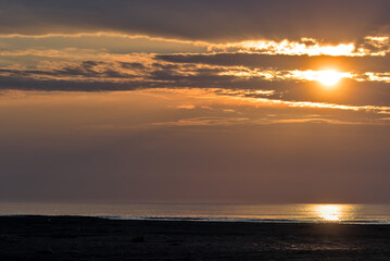 Sunrise on a foggy morning on the Black Sea coast. Beautiful seascape, early sunrise at sea and picturesque sky. Small waves and horizon line. Odessa Oblast, Ukraine.