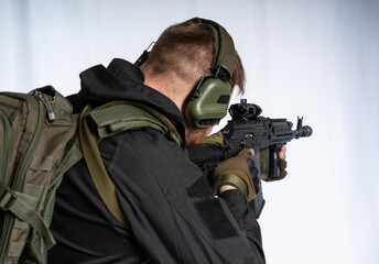 an airsoft soldier in full gear with his back to us is aiming at an optical sight. a man in an...