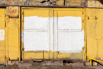 Large garage doors painted yellow smeared with white paint